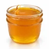 Honey oil in a clear ridged glass jar, thick golden amber oil on a white background